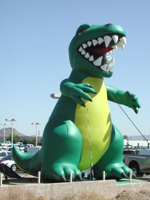 Giant green lizard sells sells used trucks.
