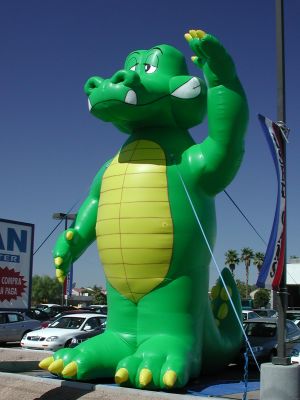 Goofy green lizard sells sells used cars.
